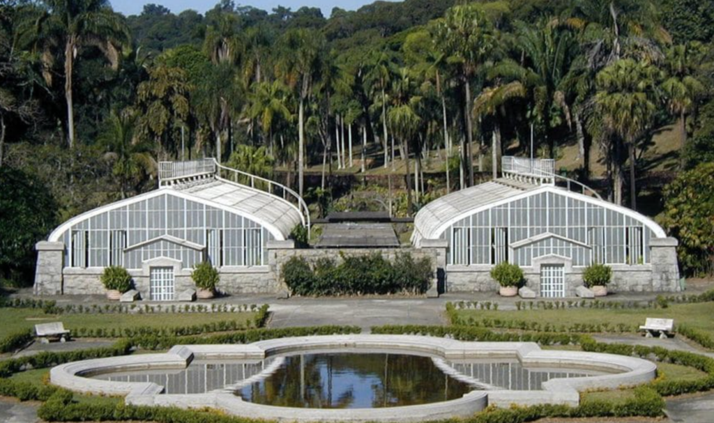 Vista do Jardim Botânico de São Paulo, mostrando suas estufas e lagoas em um dia ensolarado.