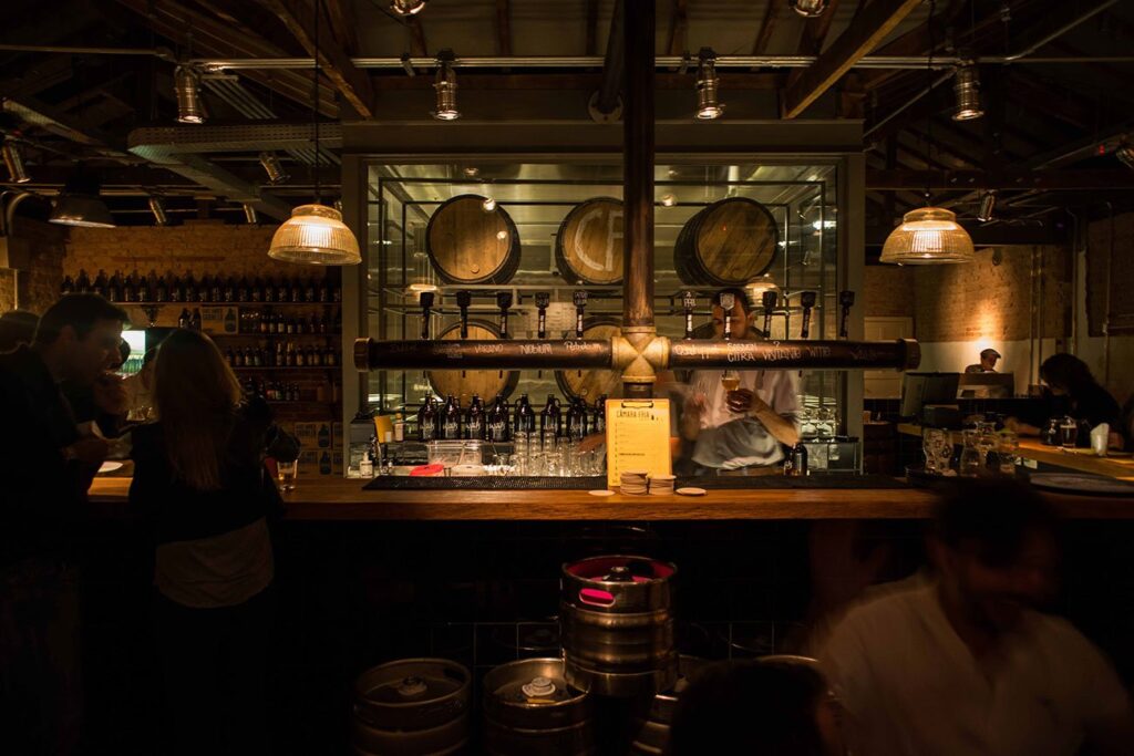 Interior do bar Câmara Fria em Moema, destacando a decoração aconchegante e as paredes de tijolo exposto.