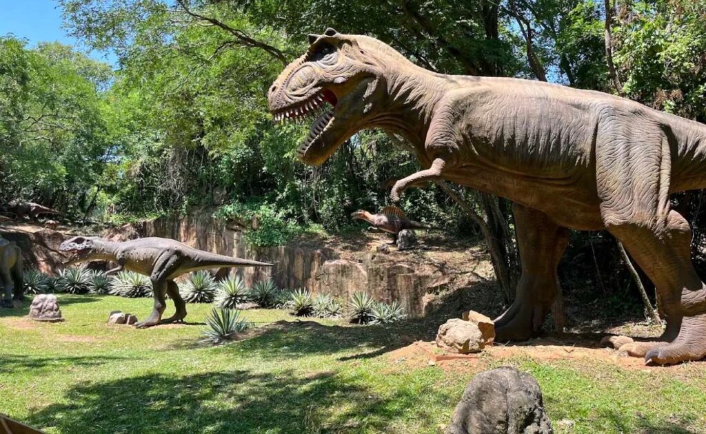 Crianças se divertindo no Parque dos Dinossauros com réplicas em tamanho real