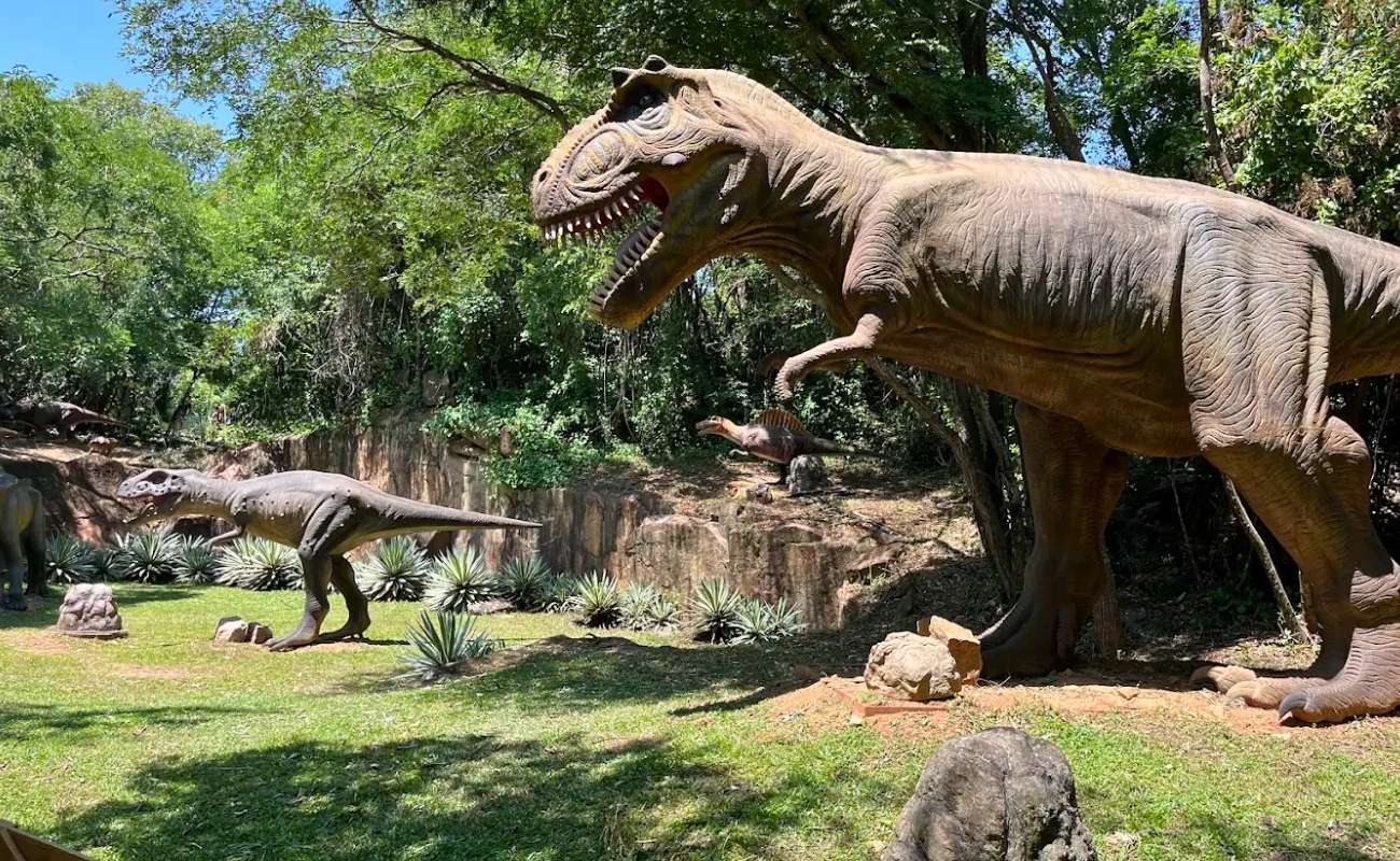Crianças se divertindo no Parque dos Dinossauros com réplicas em tamanho real