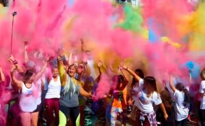 Participantes do Agita Comunidade Collors 2026 dançando e se divertindo no Parque da Juventude, com explosão de cores ao fundo.