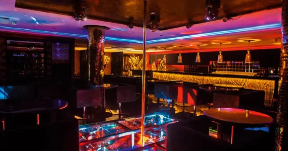 Lounge de entrada aconchegante com sofás e balcão premium de alta coquetelaria na Hot Bar Moema em São Paulo.