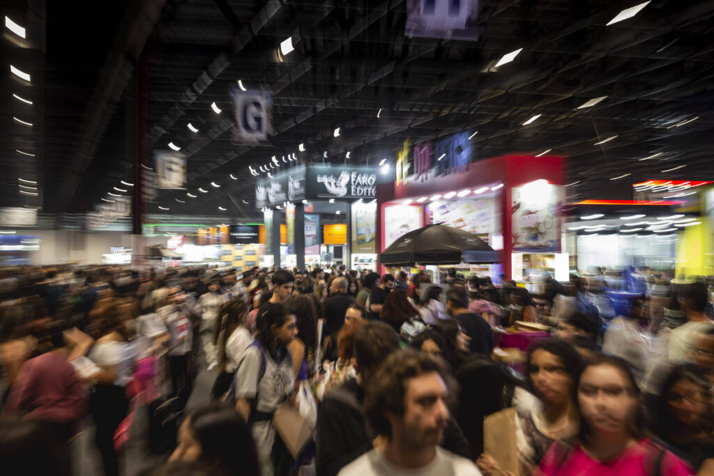 Visitantes aproveitando a Bienal do Livro em São Paulo rodeados por estandes de livros e atividades.