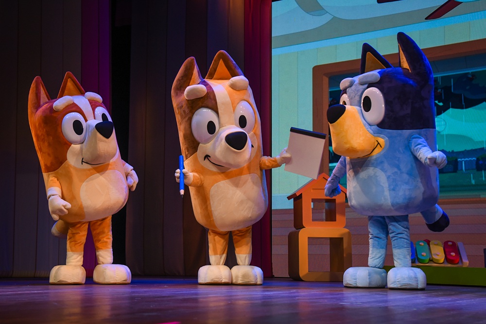 Cena do espetáculo Bluey Ao Vivo no Teatro Claro, apresentando a cachorrinha Bluey e seus amigos em uma divertida aventura.