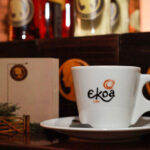 Ambiente acolhedor do Ekoa Café em São Paulo, com mesas, decoração aconchegante e clientes interagindo.