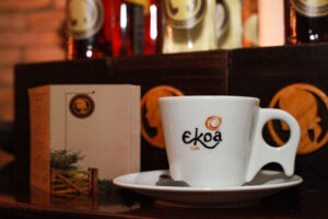 Ambiente acolhedor do Ekoa Café em São Paulo, com mesas, decoração aconchegante e clientes interagindo.